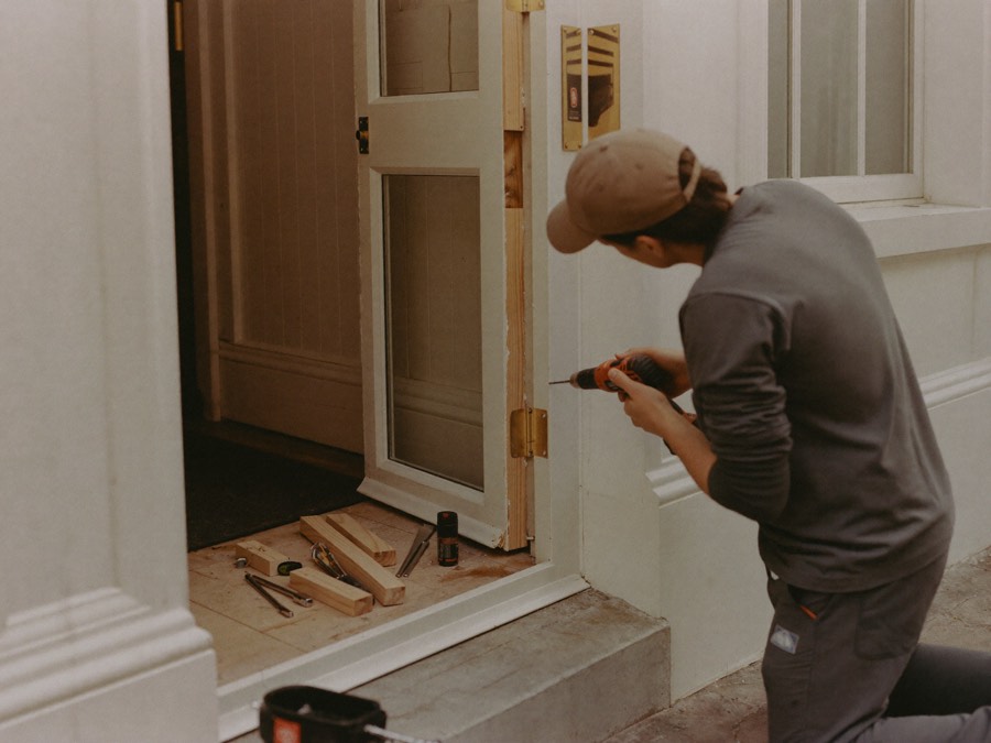 Engineer repairing a damaged front door frame after a break-in