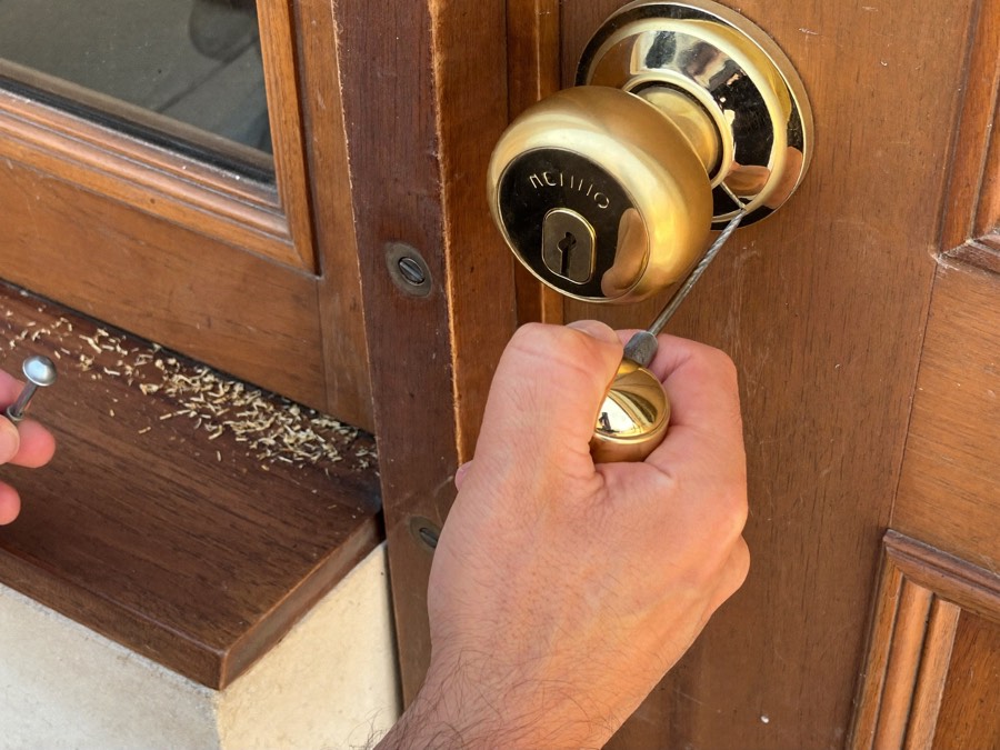 Locksmith fitting a new brass euro cylinder lock into a wooden front door