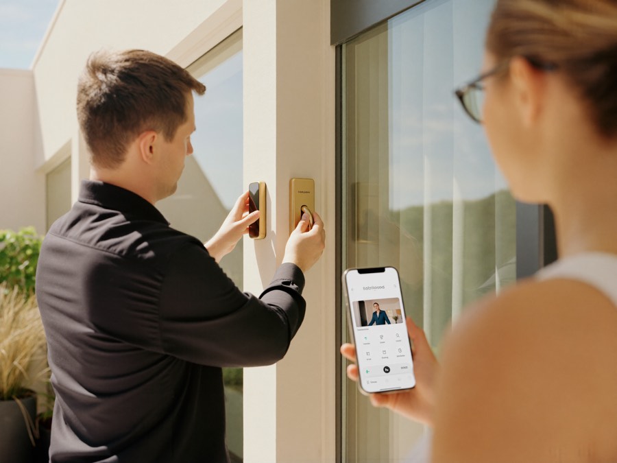 Locksmith installing a smart lock keypad while the homeowner sets up the app